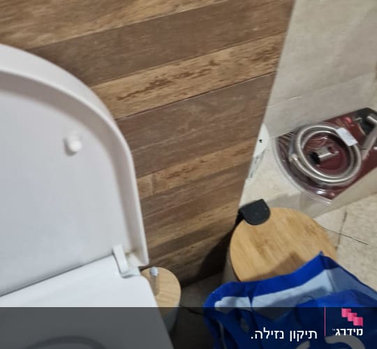 אסלה, שקית עם כיתוב, צינור מתכת על הרצפה